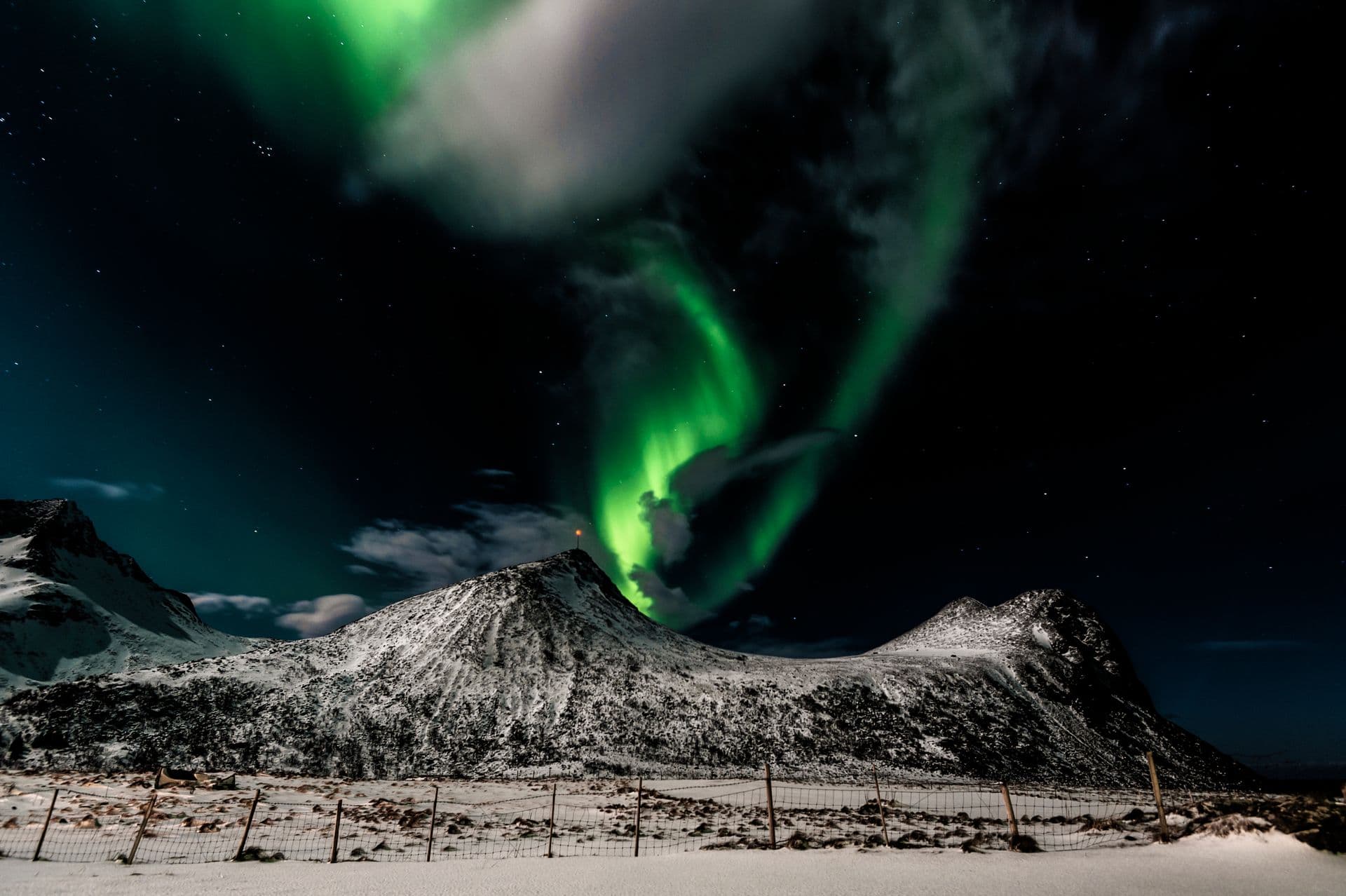 Norrsken som sveper över snötäckta Lofotenfjäll